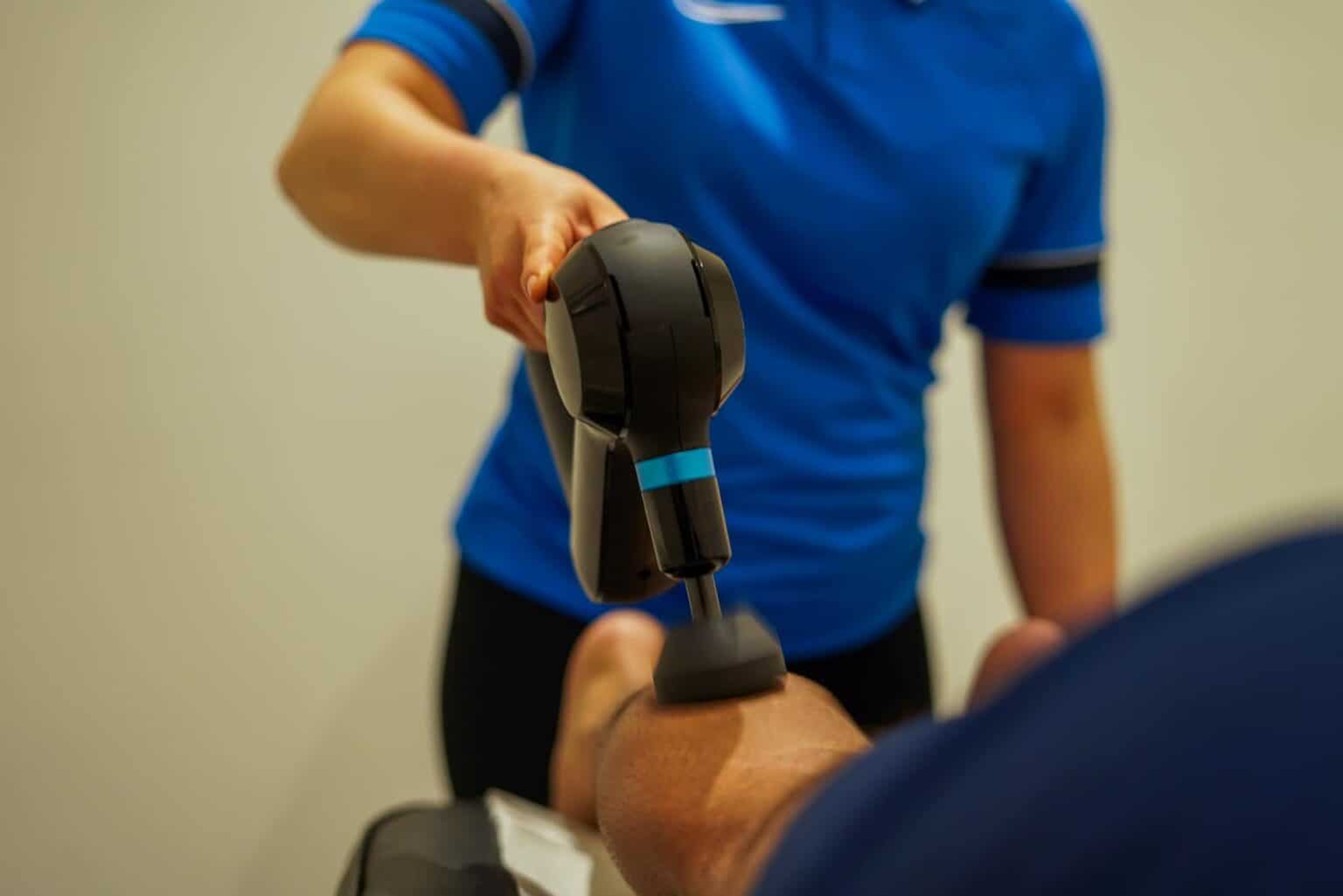 Kinetic Sports Performance staff using a massage gun